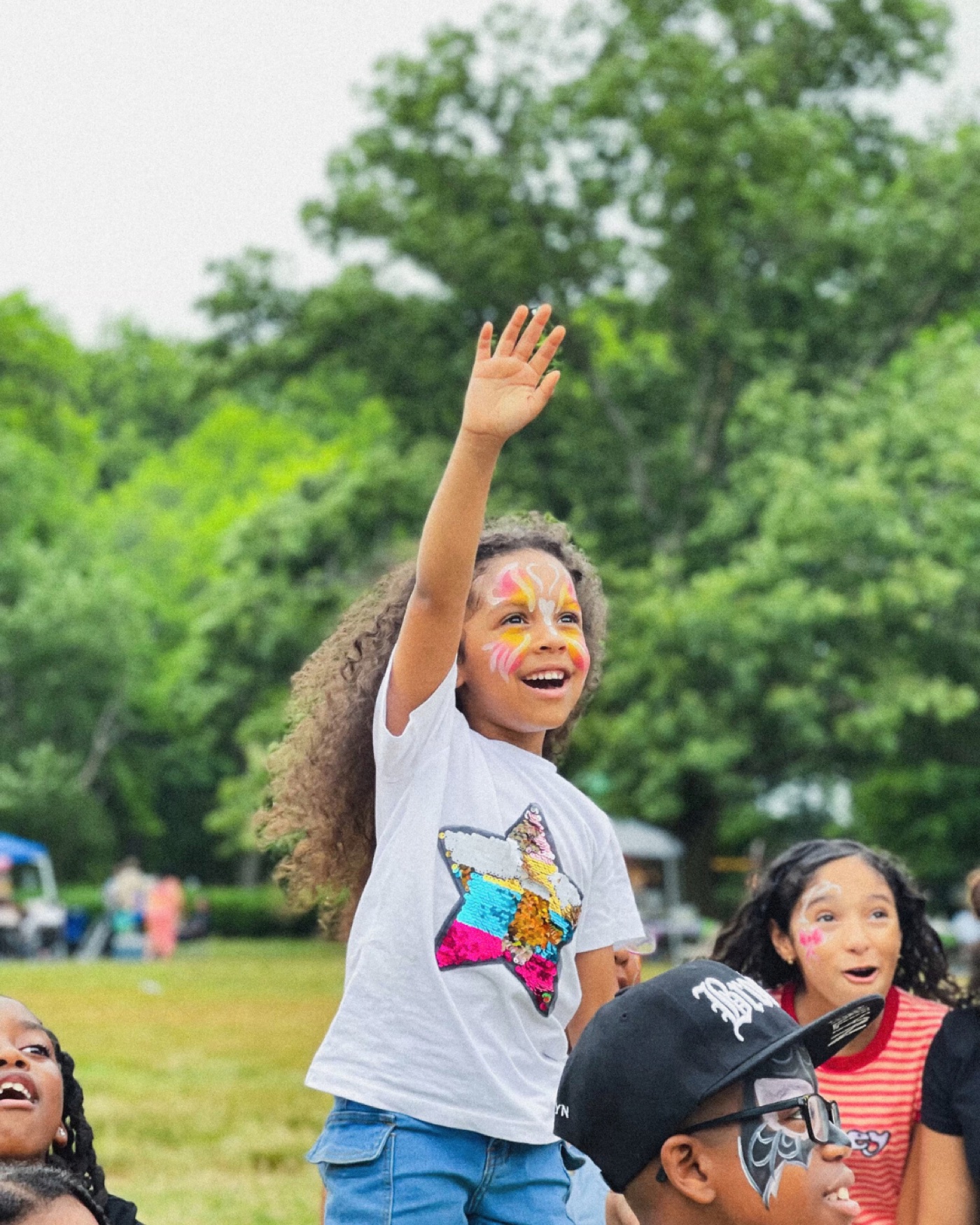 Child raising her hand and laughing during a real outdoor party