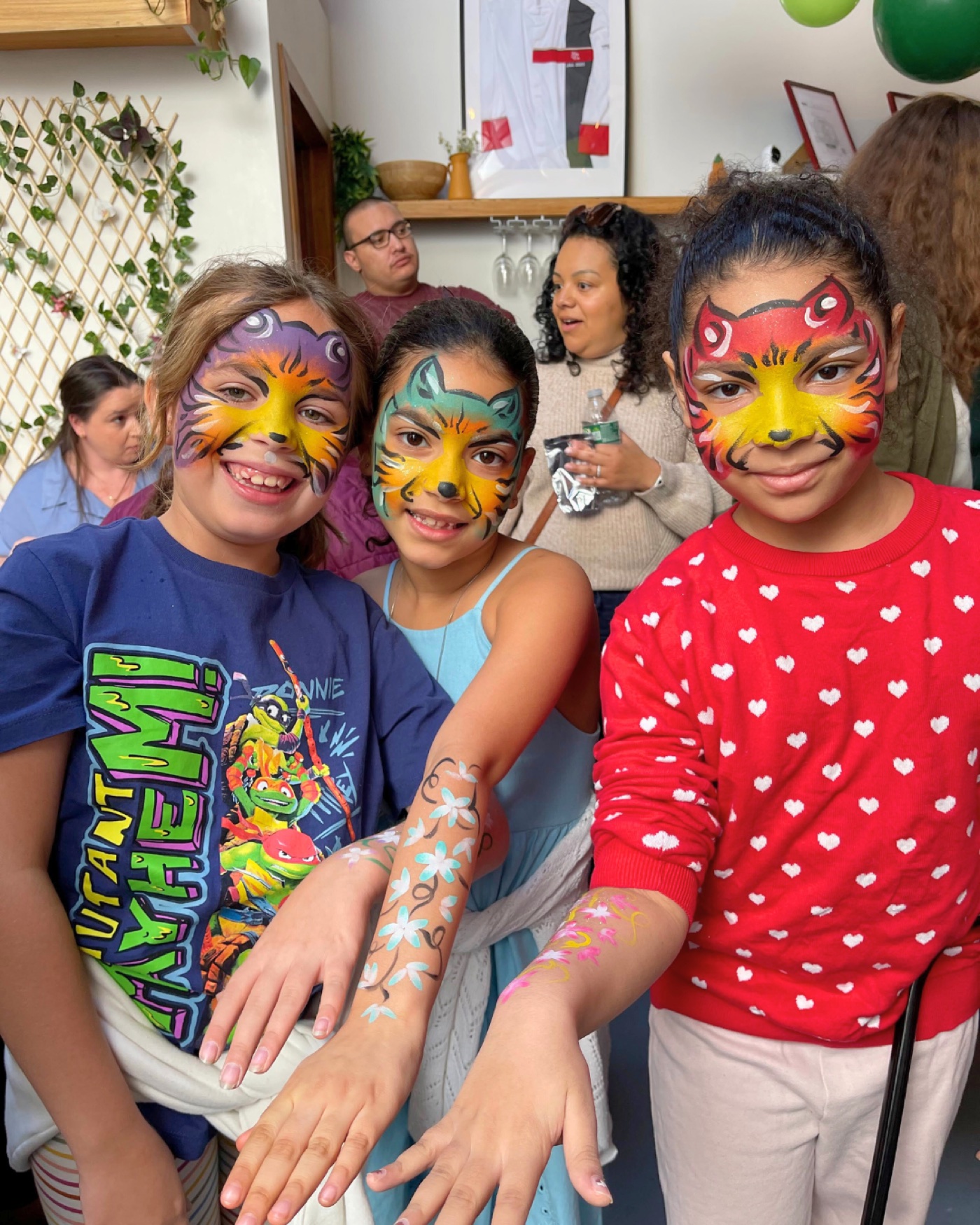 Three friends proudly showing colorful full-face paint designs