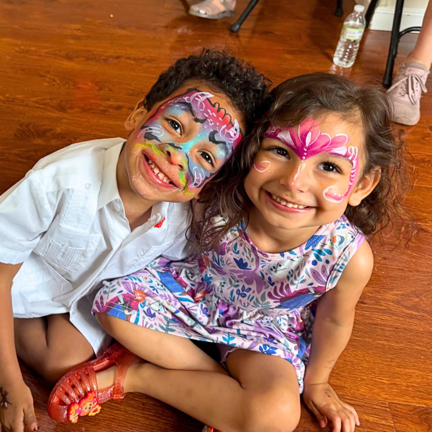 Two smiling children showing off colorful face paint at a real party